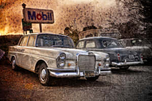 兩輛 vintage Mercedes-Benz 汽車在黃昏時停放在一個帶有褪色 Mobil 標誌的加油站。