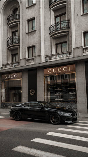 黑色豪華跑車停在城市街道上的Gucci商店前。