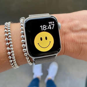 手腕上的 Apple Watch 顯示笑臉和銀色串珠手鍊。