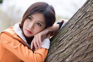 年輕女性在白天將頭靠在樹幹上休息。 — 亞洲 壁紙