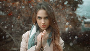 穿著冬季外套和圍巾的女性站在戶外飄雪中。 — 冬日美學 壁紙