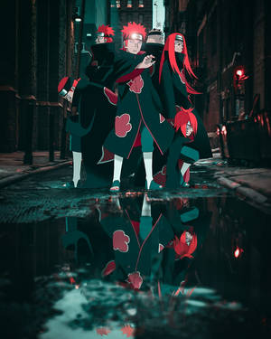 四個身穿黑色斗篷、帶有紅色雲紋的動漫人物站在下雨的小巷中，倒映在水窪中。
