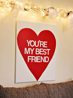 紅色心形畫布，白色文字「You're My Best Friend」，掛在串燈下。