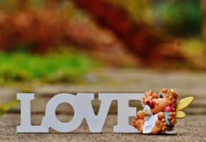 白色的LOVE字母，旁邊有一個小天使玩具在行人路上。
