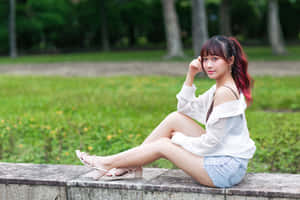 紅髮尖端的年輕女士坐在公園石牆上，穿著白色上衣和牛仔短褲。 — 可愛少女風gif 壁紙