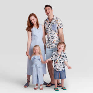 一個微笑的四口之家穿著相配的夏季服裝一起擺姿勢。