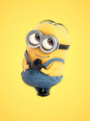 一個戴著護目鏡和牛仔布工裝褲的黃色卡通Minion交叉雙臂微笑。