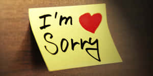 木質表面上一張黃色便利貼，寫有「I'm Sorry」和一個紅色心形。