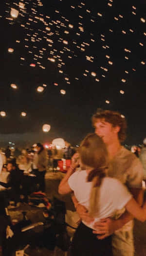 一對情侶在夜間擁抱，發光的燈籠漂浮在他們上方。 — 可愛情侶 GIF 壁紙