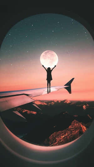 人站在飛機機翼上在暮色中伸手觸摸月亮