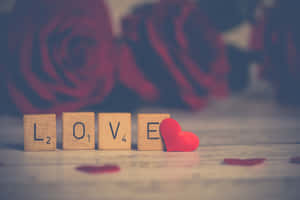 木製字母拼出 LOVE，背景有紅心和柔焦的玫瑰。