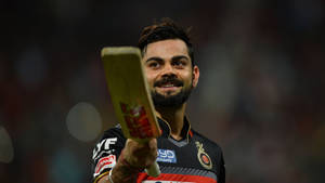 板球運動員 Virat Kohli 在夜間微笑著手持球棒。 — 巴基斯坦板球 壁紙