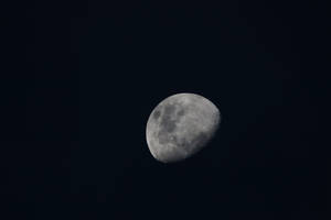 在黑暗夜空中可見隕石坑的彎月