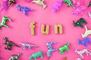 色彩繽紛的閃亮恐龍玩具在粉紅色背景上圍繞著「fun」字。