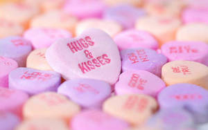 柔焦中帶有紅色訊息（如 hugs kisses）的粉彩心形糖果。