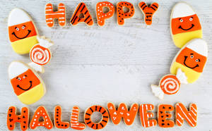 Happy Halloween 餅乾，形狀像糖果玉米和棒棒糖，放在白色木質背景上。