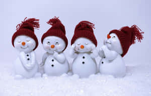 四個戴著紅色帽子的微笑雪人公仔坐在雪中。