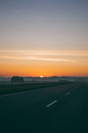 日出時空無一人的高速公路，有霧和橙色天空