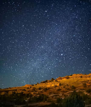 溫暖燈光照耀下的沙漠山丘上的星空之夜。