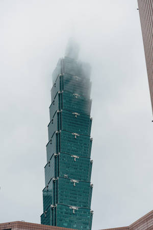 現代玻璃摩天大樓在多雲天氣下部分被霧雲遮擋。 — 花城 壁紙