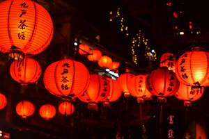 帶有黑色字符的紅色紙燈籠照亮了繁忙的夜晚街道。 — 唐人街 GIF 壁紙