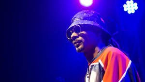Snoop Dogg 在藍色燈光下戴著漁夫帽和太陽眼鏡在舞台上表演。