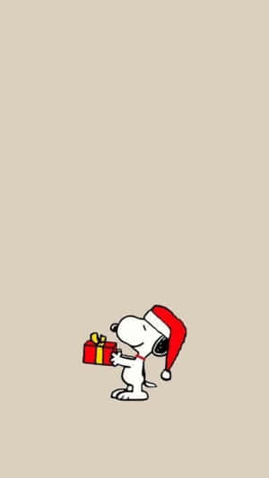 戴著聖誕帽的史努比拿著一個包裝好的禮物盒。