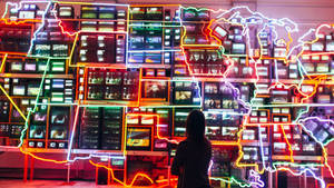 觀看由霓虹燈勾勒出地圖形狀的電視牆的人。