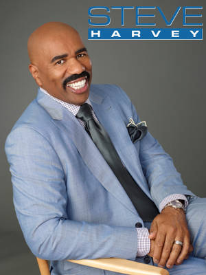身穿藍色西裝的 Steve Harvey 對著鏡頭溫暖微笑。 — 灰色 GIF 壁紙