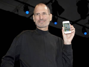 史蒂夫·喬布斯在藍色聚光燈下於舞台上舉起一部白色iPhone。