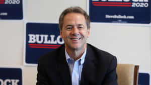 Steve Bullock在2020年競選活動中微笑，背後有品牌海報。 — 政治 壁紙