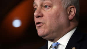 穿著西裝的男子在正式活動中說話，背景模糊。 — 政治 壁紙