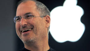 Steve Jobs 微笑，背後有 Apple 標誌