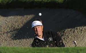 Golfer hitting golf ball out of sand bunker with sand flying around him. — 高爾夫球 iPhone 壁紙