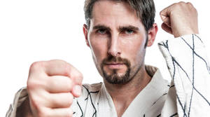一名穿著武術制服的男人帶著堅定的表情向前出拳。