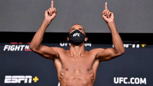 赤裸上身的UFC拳手戴面罩在稱重活動中向上指。