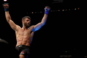 一位勝利的MMA拳手在競技場燈光下高舉雙臂慶祝。