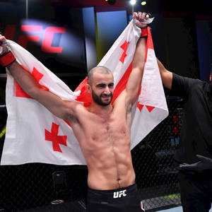 UFC拳手在八角籠內手持格魯吉亞國旗慶祝勝利。 — 冠軍 壁紙