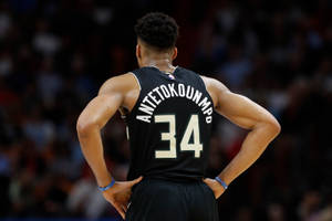 籃球運動員Antetokounmpo身穿黑色34號球衣，雙手叉腰。