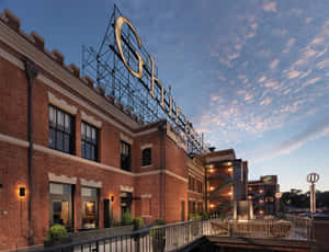 黃昏時的 Ghirardelli 朱古力工廠，帶有發光標誌和戶外座位。 — 天際線 壁紙