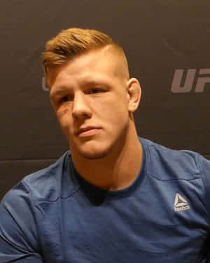 男性UFC拳手臉頰上有瘀傷，在記者會上穿著藍色Reebok襯衫。 — 肖像 壁紙