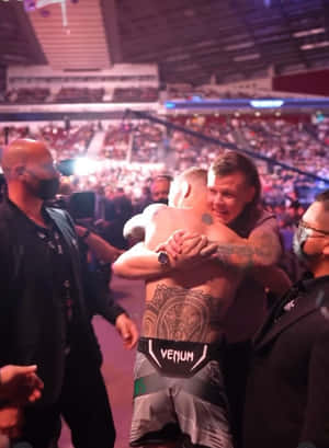 兩名MMA拳手在擠滿觀眾的場館內比賽後擁抱。 — 搏擊會 GIF 壁紙