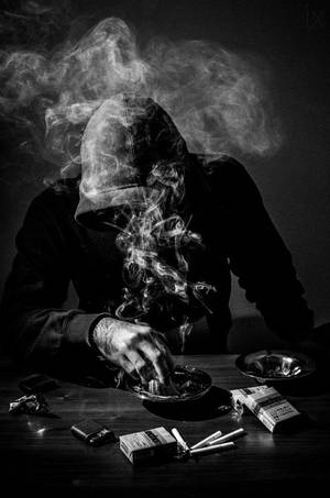 一個戴著兜帽的人抽煙，煙霧在他們的臉龐周圍升起。