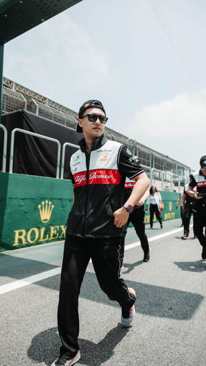賽車手穿著 Alfa Romeo 裝備和太陽眼鏡在賽道上行走。