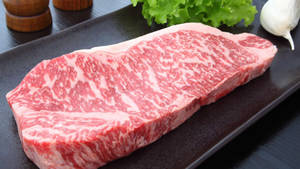 高品質的大理石紋牛肉扒，配以生菜和大蒜。