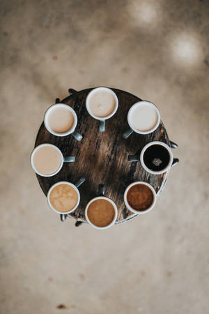 Seven coffee mugs in a circle on a wooden table with concrete floor. — 美學 壁紙