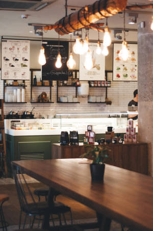 舒適的現代咖啡館，配有木桌、吊燈和瓷磚牆上的菜單板。