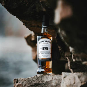 水邊石頭上的Bowmore 12年威士忌酒瓶。