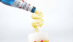 一瓶Kronenbourg 1664啤酒將金色液體倒入帶有泡沫的玻璃杯中。