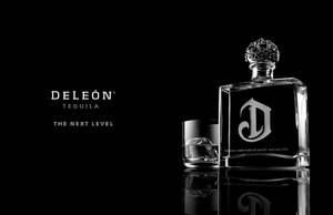 Deleón龍舌蘭酒瓶和加冰的酒杯在反光黑色表面上